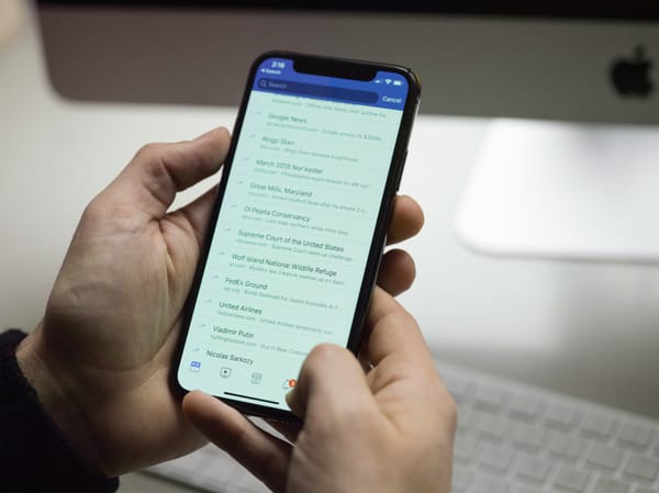 Hands holding a smartphone showing trending topics on Facebook