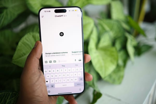 ChatGPT open on a smartphone screen, held by a hand against a backdrop of plants