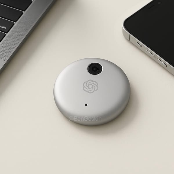 A hockey puck-shaped white device with a camera and the OpenAI logo on it sitting on a desk